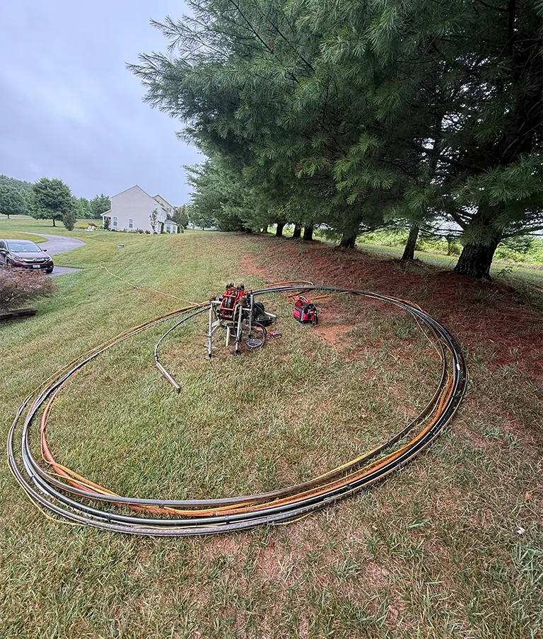 A long coil of new well pipe and wire laid out on a lawn before going down the well