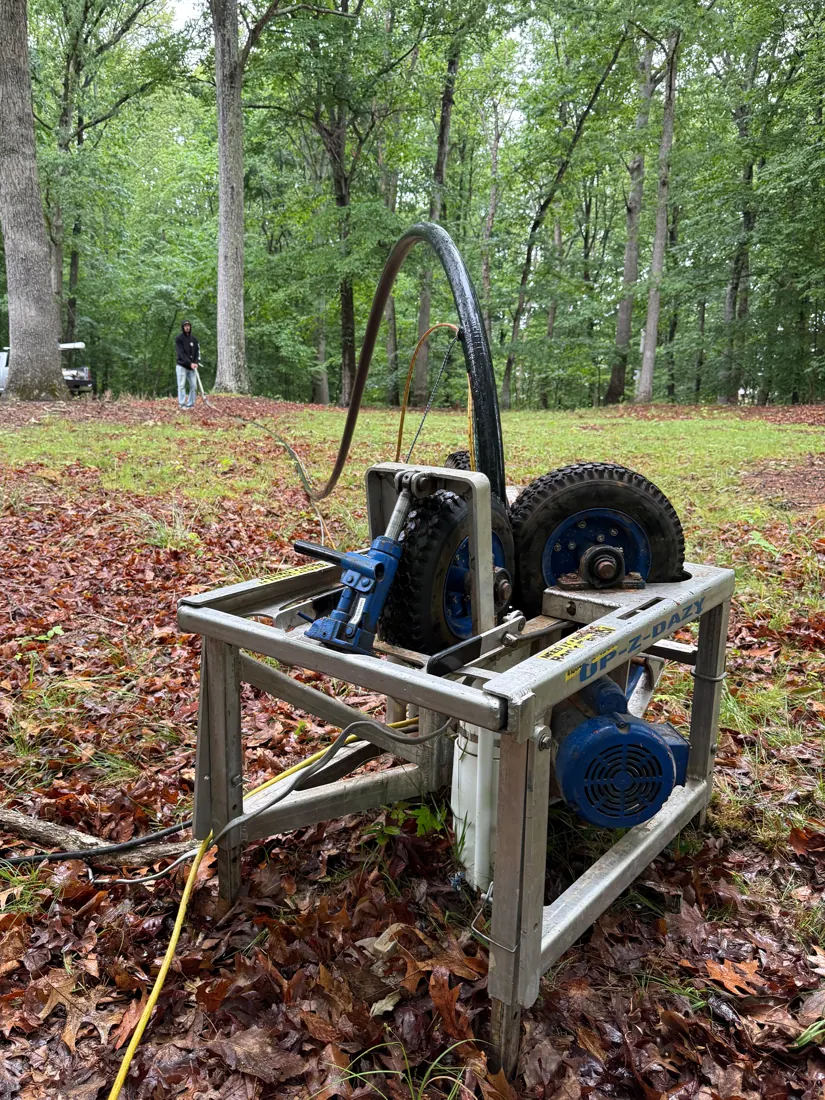 A new submersible pump beside a pump-pulling machine next to a wellhead in a garden bed