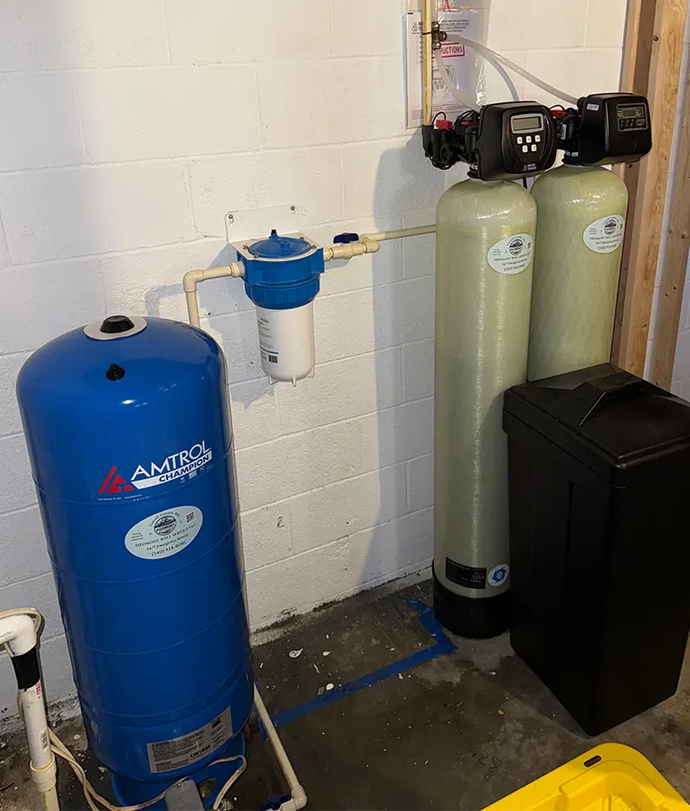 A blue Amtrol pressure tank, sediment filter, softener and brine tank installed in a basement