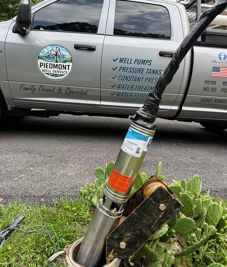 A new submersible pump at the wellhead in front of the Piedmont Well Service truck, lettered Family Owned & Operated
