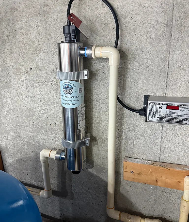 A stainless UV disinfection unit and its controller mounted on a basement wall