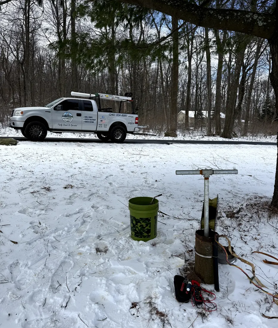 The Piedmont Well Service pickup parked in snow, with a well pump pulled up at the wellhead